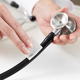 Ruky utierajúce hadičky fonendoskopu Littmann pomocou tampónu namočeného v alkohole.