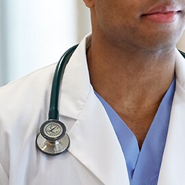 Fonendoskop Littmann zavesený správne na golieri bieleho plášťa, aby sa hadičky nedotýkali krku zdravotníka.